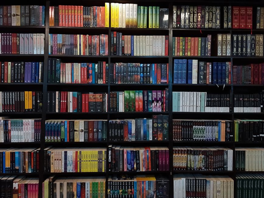 Diverse collection of books on a library shelf in Dhaka, Bangladesh.