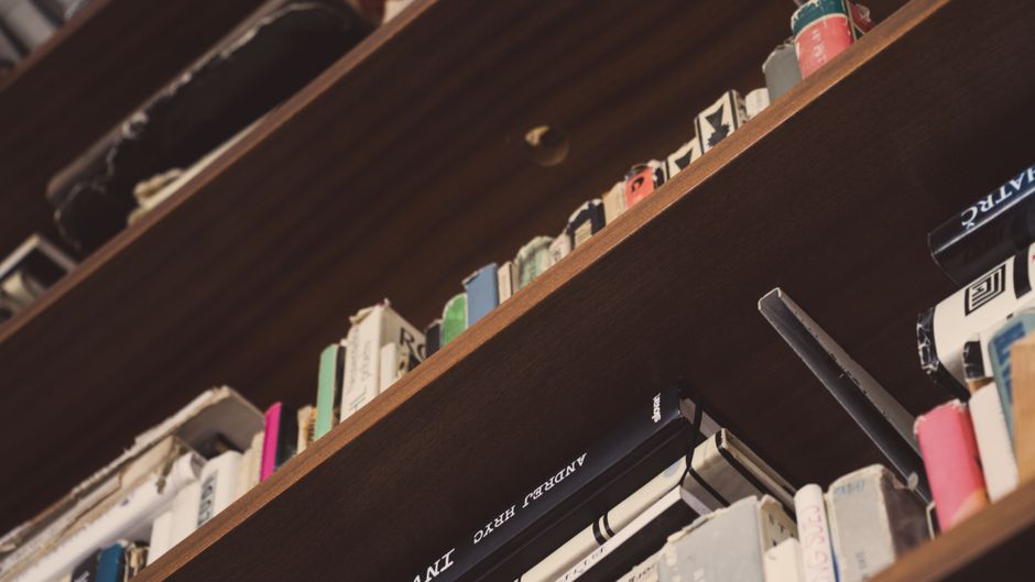 A smartphone rests on a wooden table beside an open book with pages forming a heart.